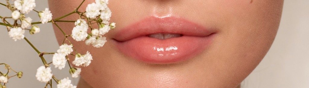 Detalle de labios melocotón con brillo y paniculata