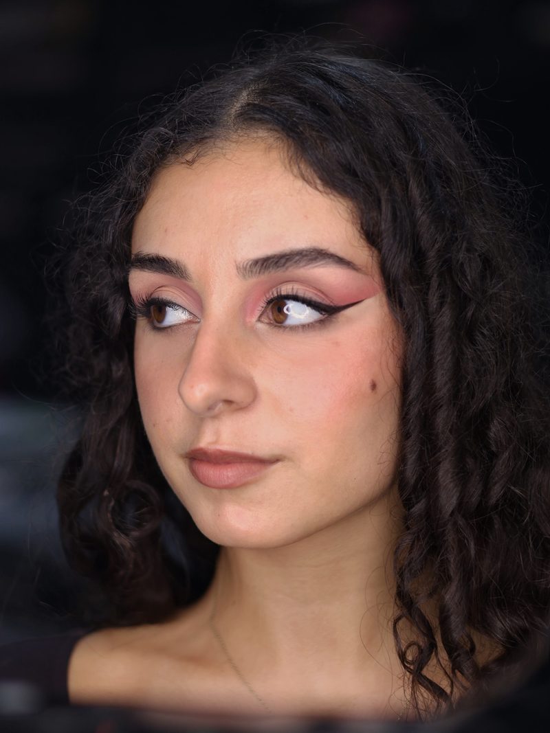 Profile of a pink winged eye look with a nude lip